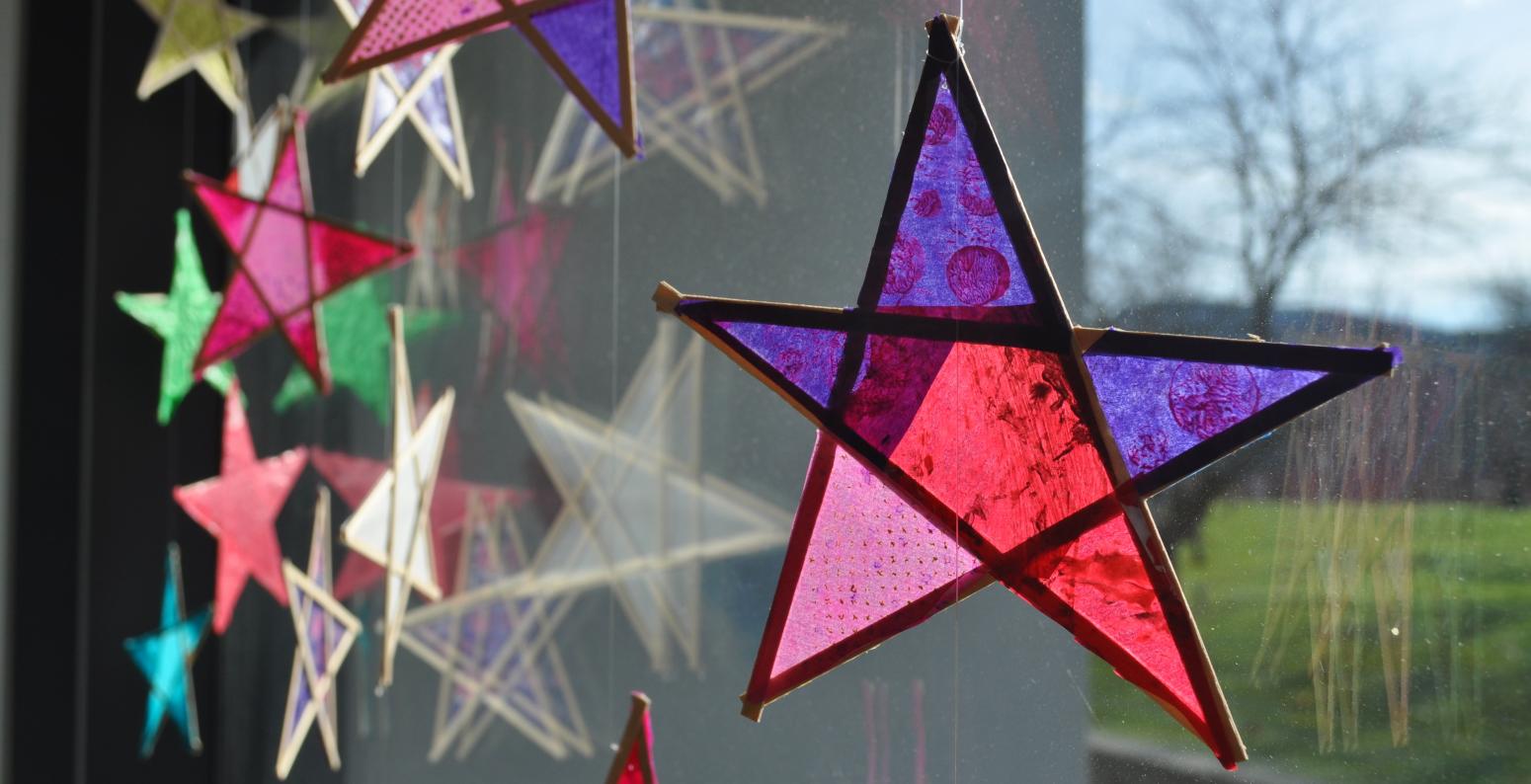 A window with wax-paper and wooden stars hanging in it.