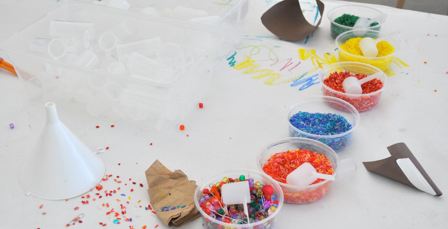 An array of colorful beads, seeds, and grains as well as funnels.