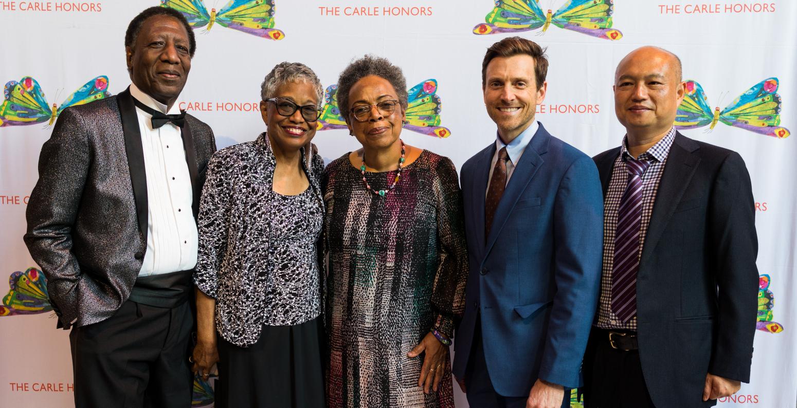 Five people stand in front of a picture of butterflies with the words The Carle Honors