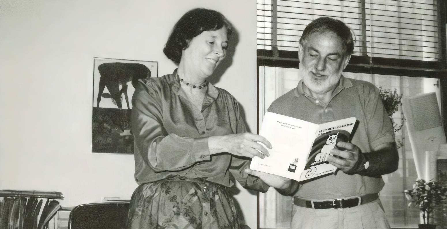 Photograph of two people reading a book together. 