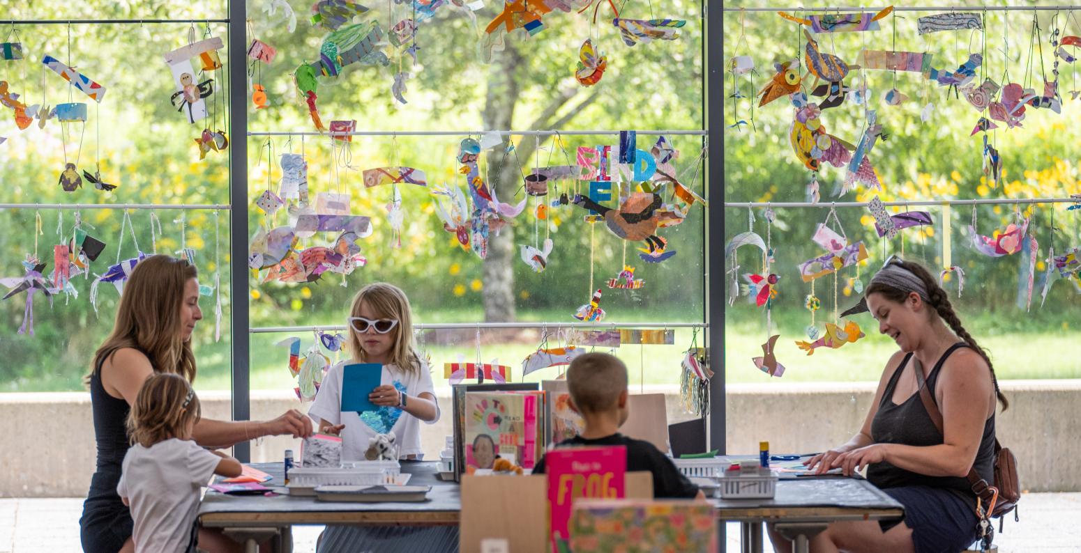 adults and kids in the art studio sitting at a table making art
