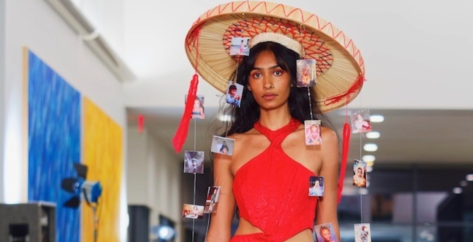Model walking down the runway with yellow skirt and red halter top