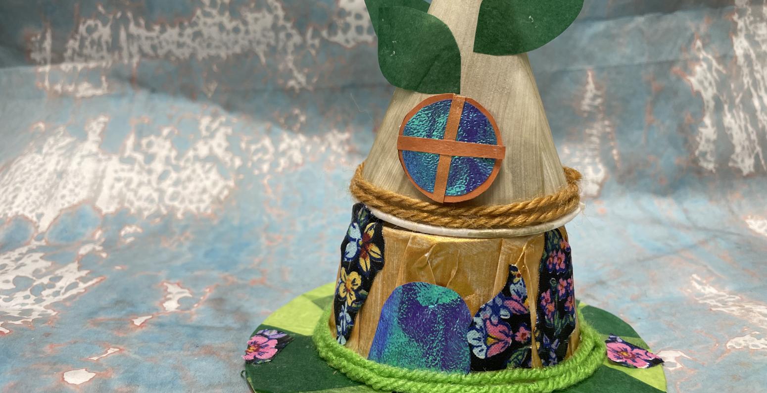 A fairy house made out of paper obects, paper leaves, sparkly papers, green fabric patches of grass