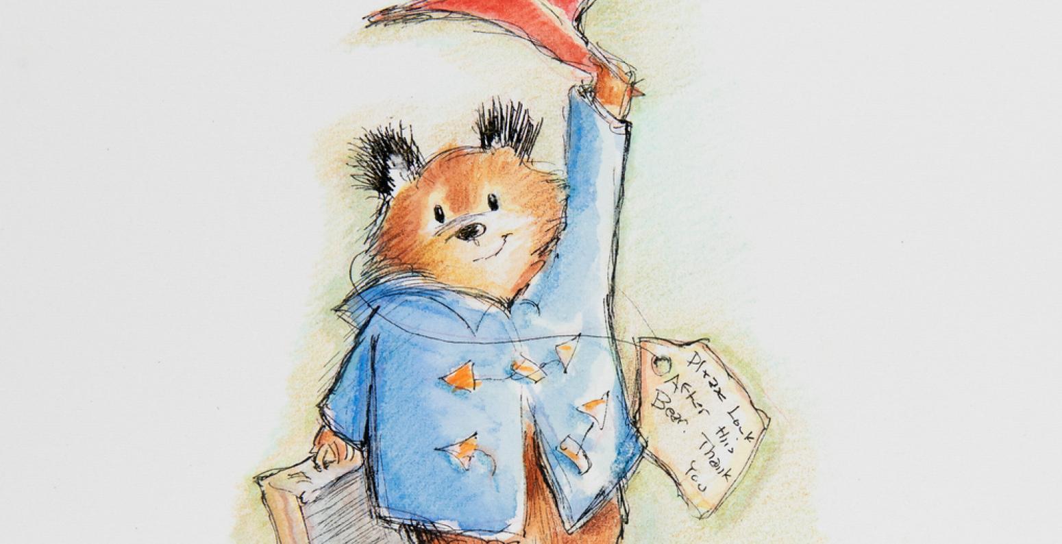 Paddington tipping his hat while holding a suitcase.
