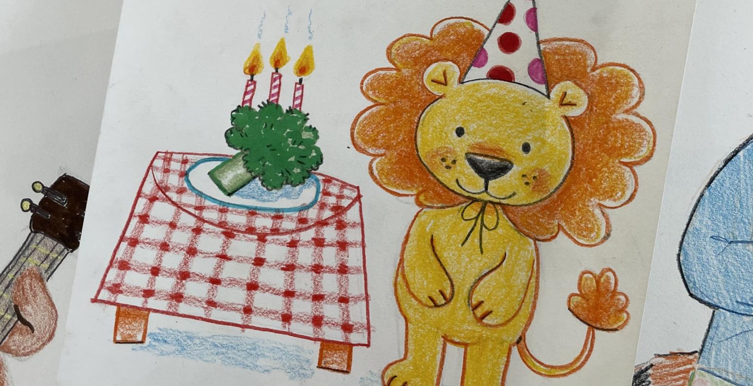 Drawing of a lion with a birthday hat on its head next to a picnic table that has a plate of broccoli with birthday candles in it. 