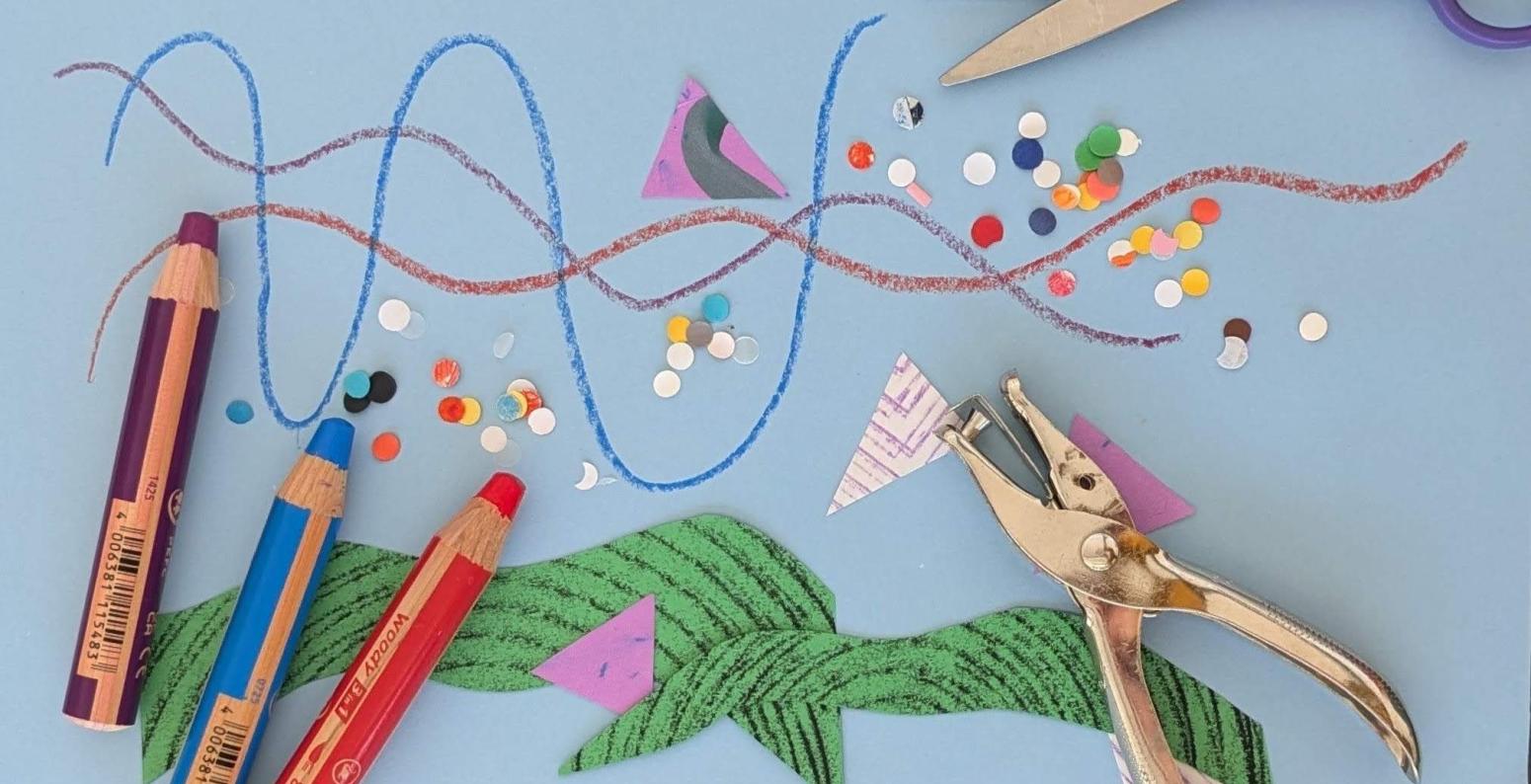 An array of art-making materials on a light blue surface. Paper shapes and hole punches scatter the scene, scissors, hole puncher, and large crayons are shown. 