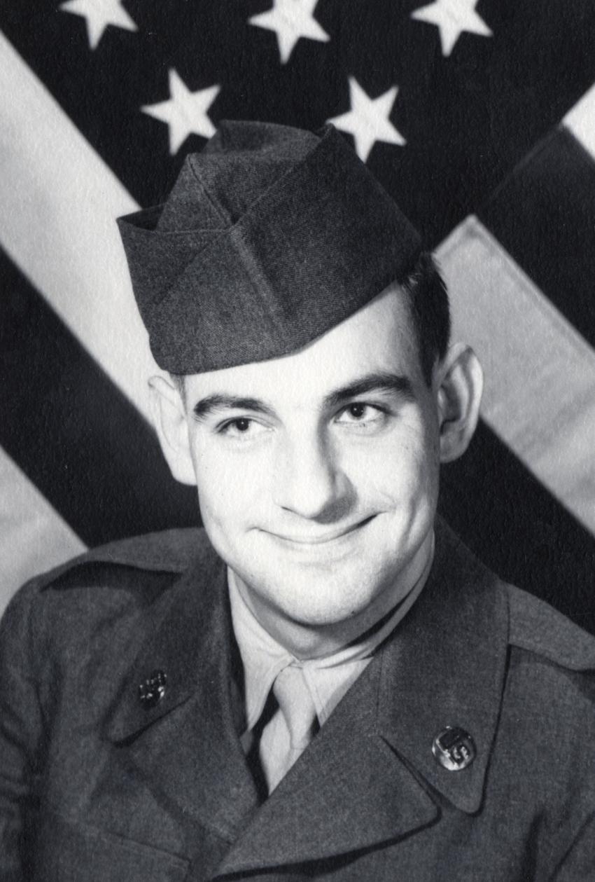 black and white photograph of Eric Carle in military uniform with American flag behind him
