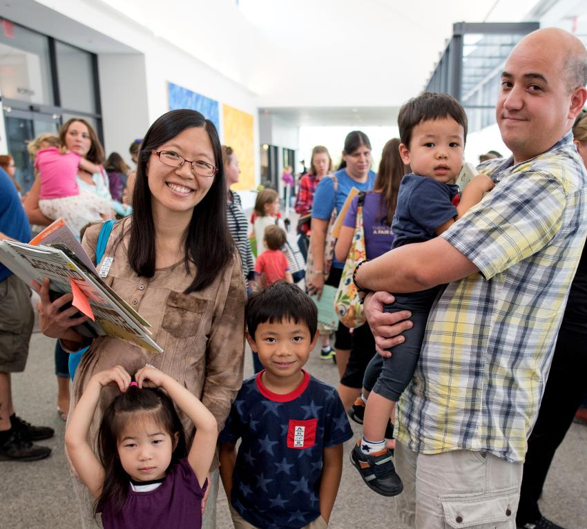 parents stand with 3 young children during a book signing event in Great Hall