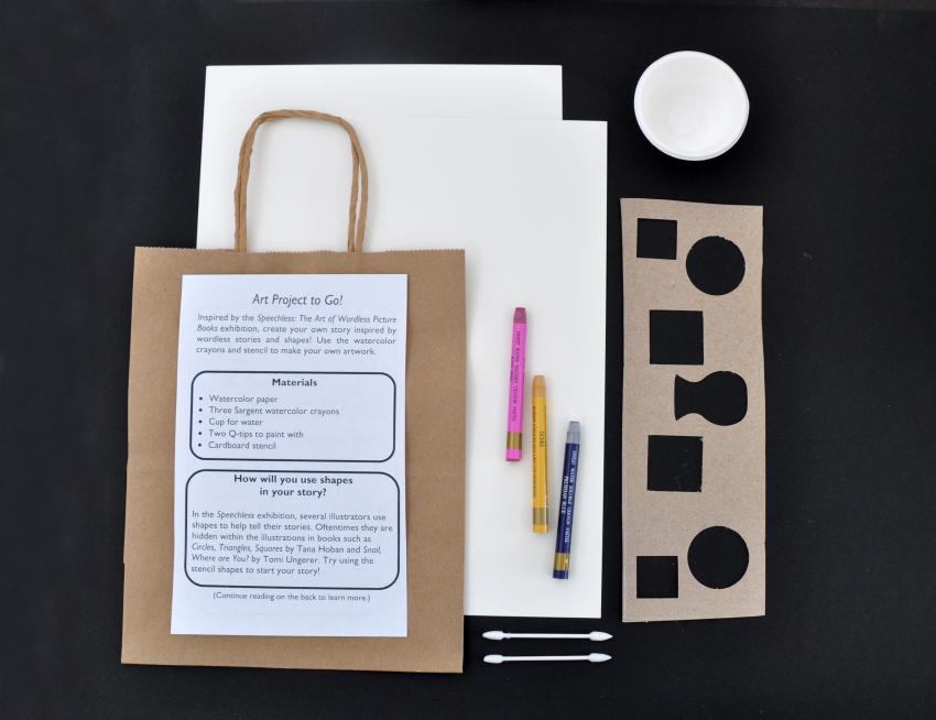 The materials within a watercolor to-go bag: a cup, two cotton swabs, a stencil, three watercolor crayons, two watercolor papers, a paper bag, and a flyer. 