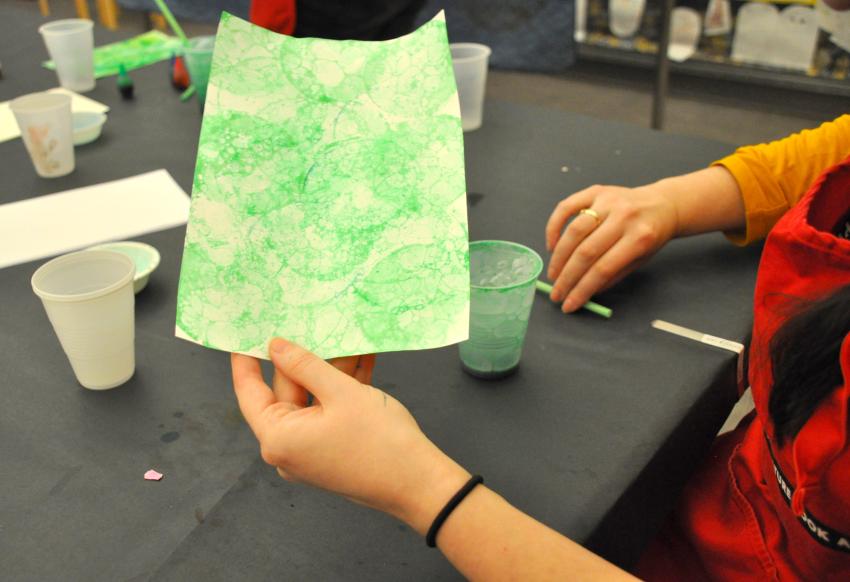 Participant holds up their green, bubble-printed paper.