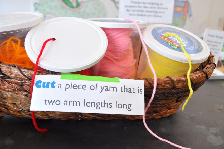 Yogurt containers with holes cut in the top used as yarn holders where artists can pull threads out of the hole in the lid, and cut their own pieces.
