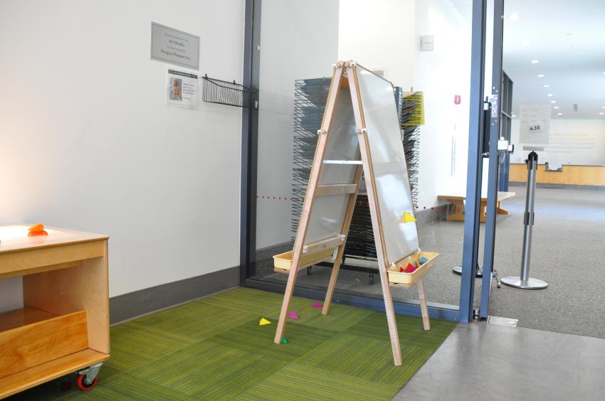 An easel with magnets on it standing on a carpet space.