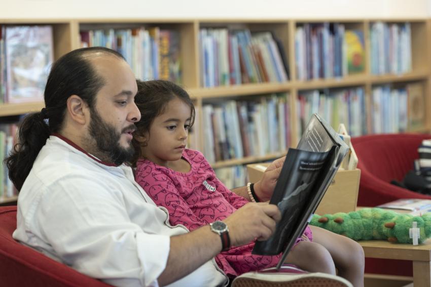 Caregiver reading with child in lap.