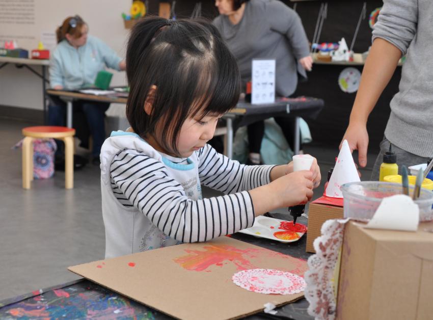 A young artist squeezes paint into a paint palette to mix a pink color.