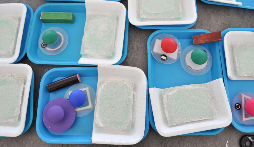 Several homemade stamp pads arranged on a table with different stamping materials. 