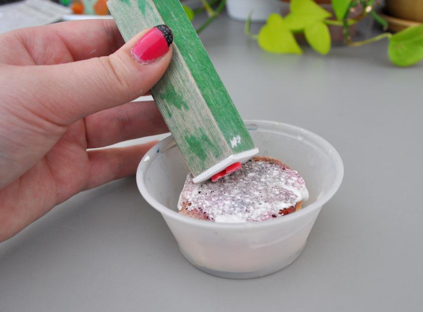 A hand pressing a homemade stamper into a cup with a small stamp pad. 