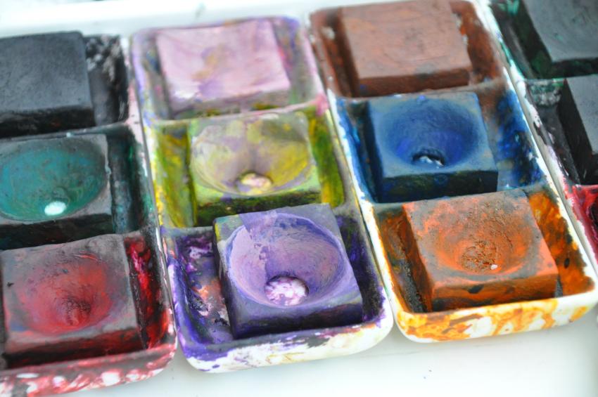 Messy trays of square tempera paint cakes.
