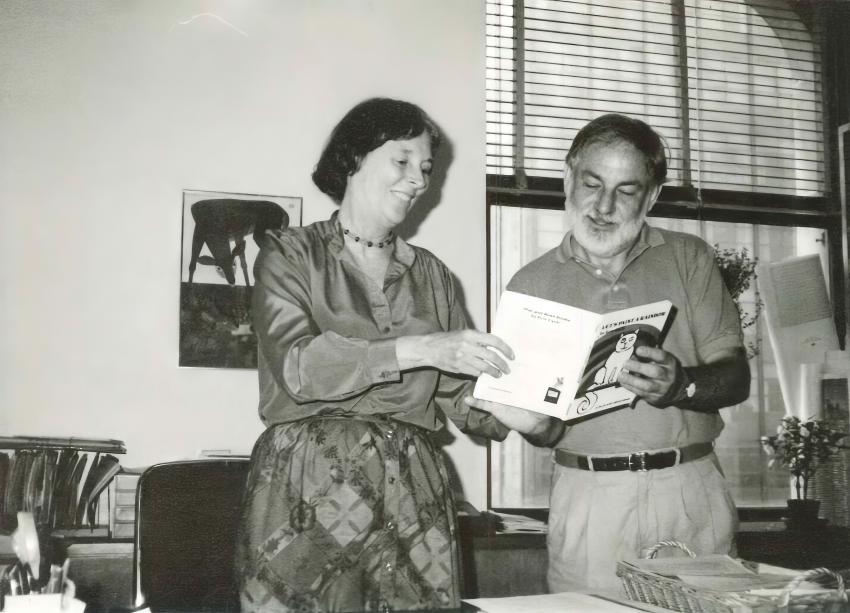 Photograph of two people reading a book together.
