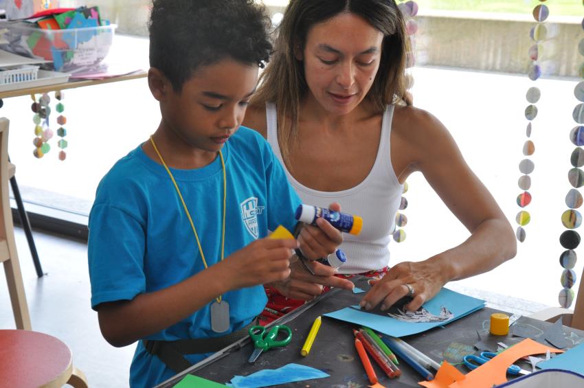 Two guests working side by side creating books. Collage papers, glue and colored pencils are being explored
