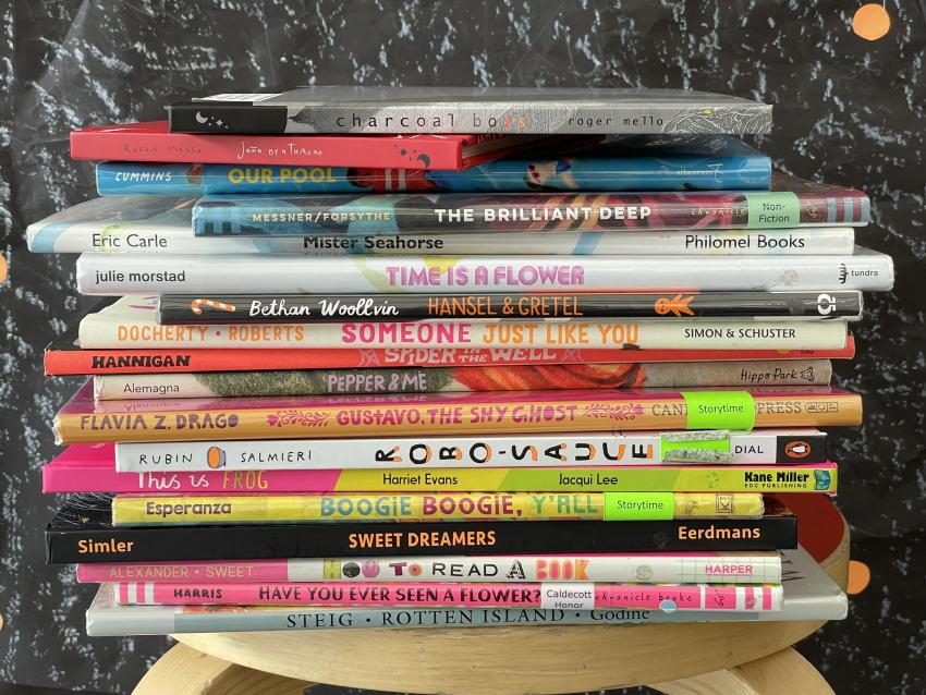 A vibrant pile of books stacked on a stool with the spines visible.