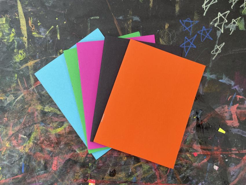 A spread of five colorful books. Blue, green, pink, black and orange.