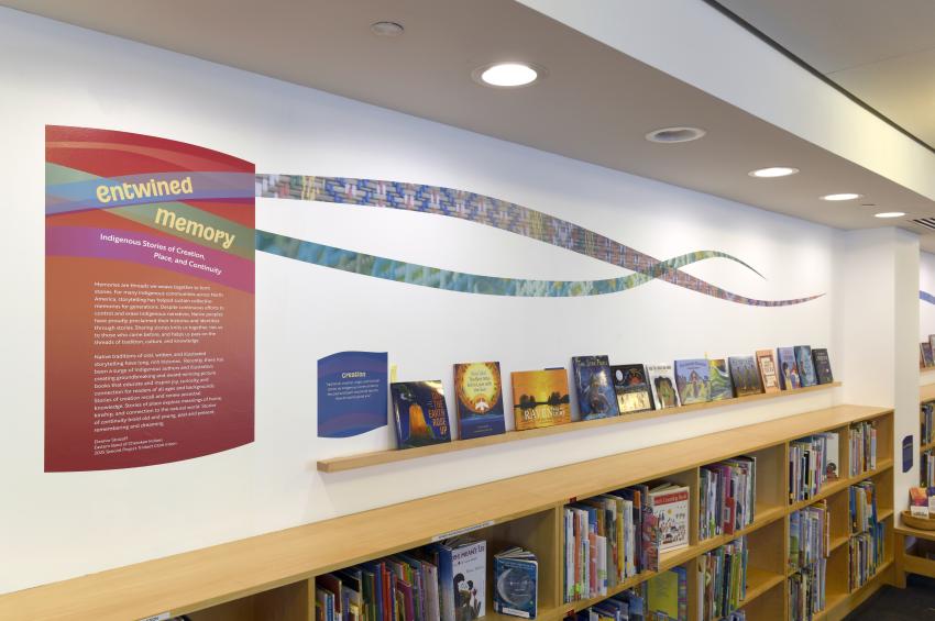 Photograph of library shelves with vinyl designs above. 