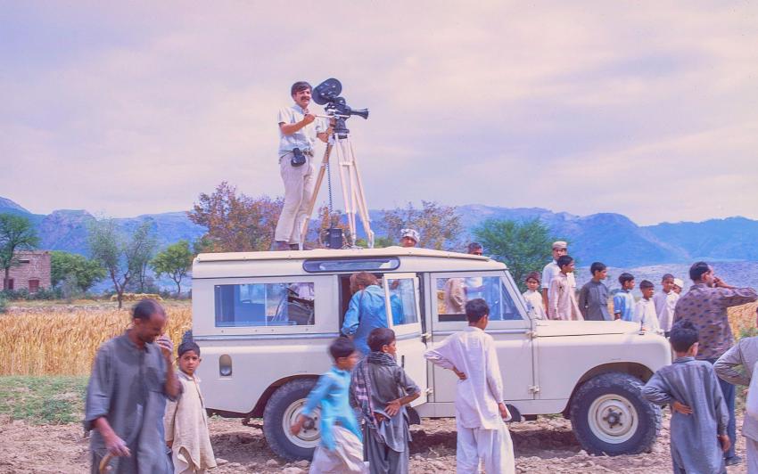 Phtoograph of director on top of car. 