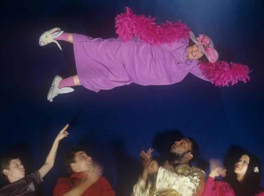 Photograph of woman flying over crowd. 