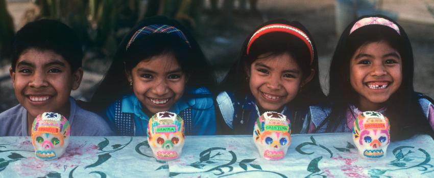 4 children at table with decorative skulls. 