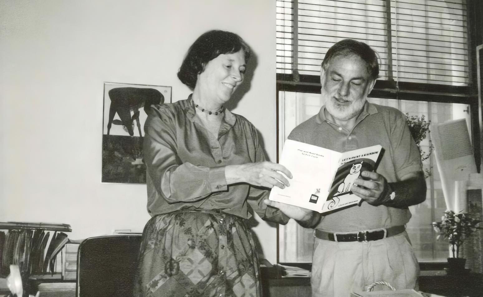 Photograph of two people reading a book together. 