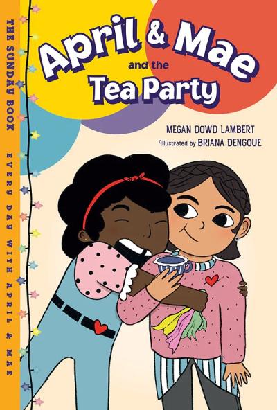 A girl wearing overalls hugs a girl holding a cup of tea.
