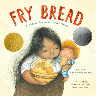 A woman holds a bowl of fry bread in one arm and a baby eating fry bread in the other.