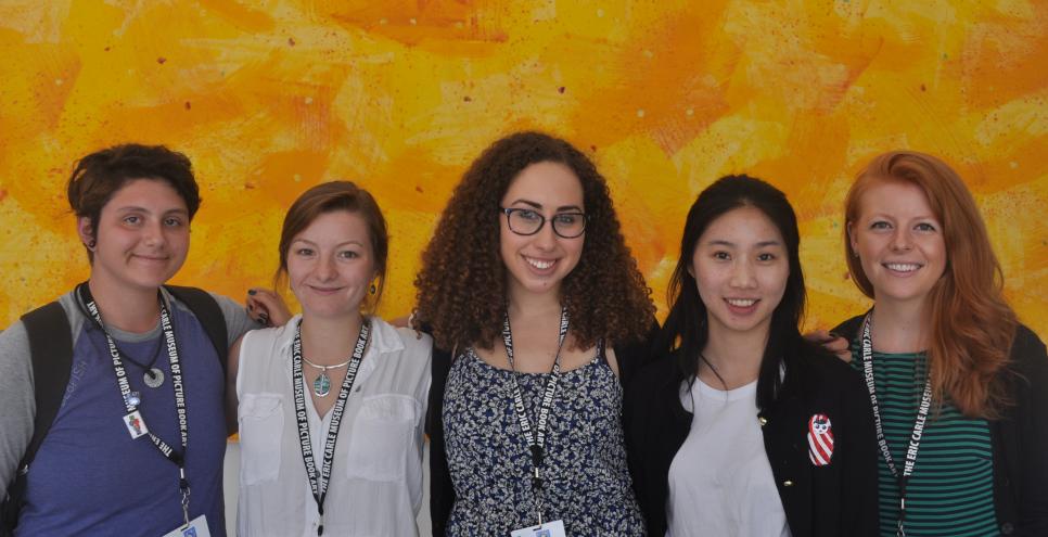 Five interns standing in front of yellow mural.