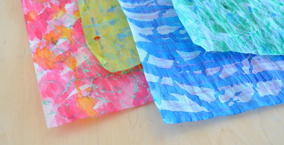 Four watercolor-painted tracing papers stacked on top of each other in the colors red, yellow, blue, and green.