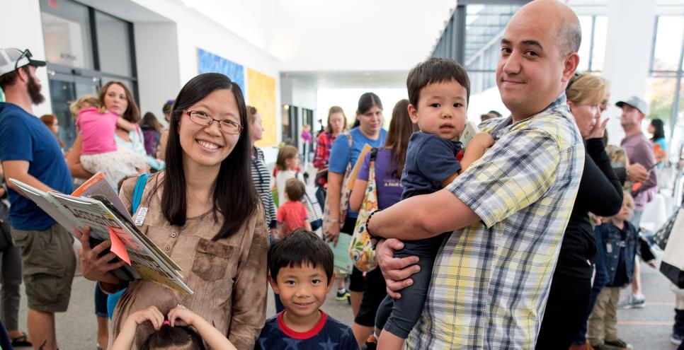 parents stand with 3 young children during a book signing event in Great Hall