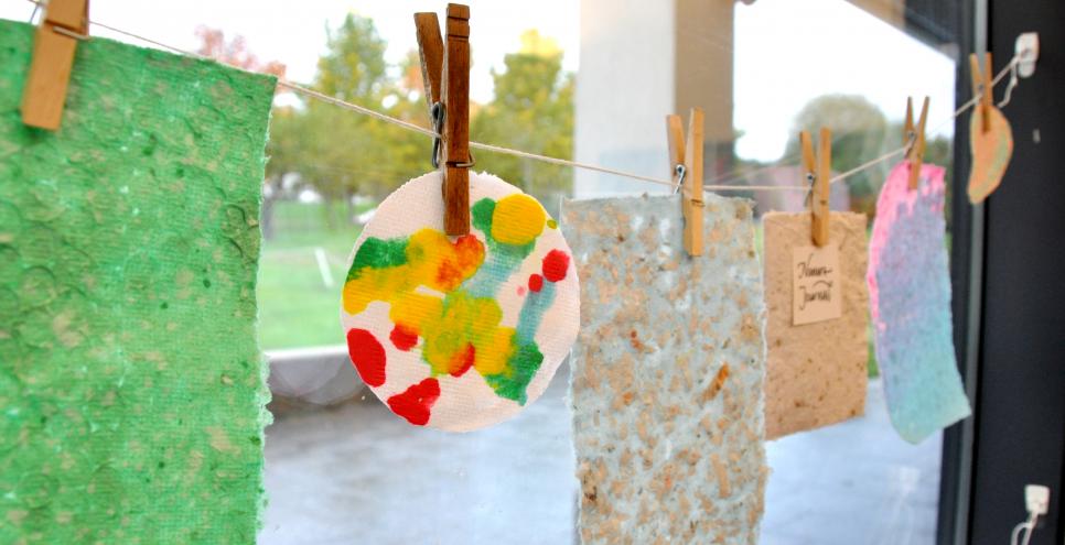 A clothesline with handmade paper clipped to each clothespin.