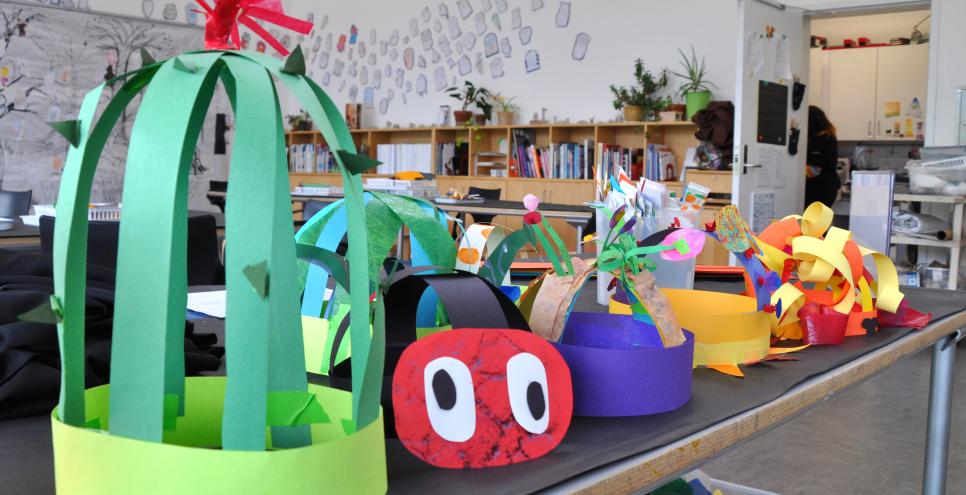 A colorful display of paper hats, one is a cactus, another a lion, and another is a ladybug.