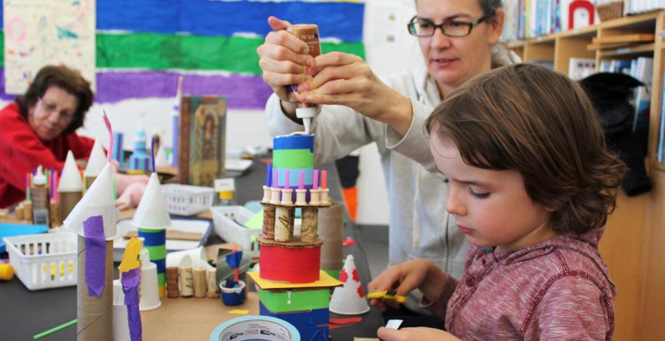 An adult and child working together to construct a tower sculpture.