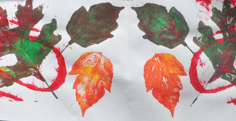 A mirror-image print with painted leaves, and a red squiggle line through them.