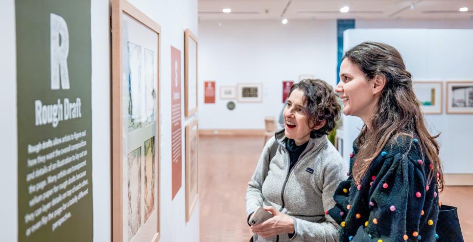 Two adults smiling while looking at art in an exhibition