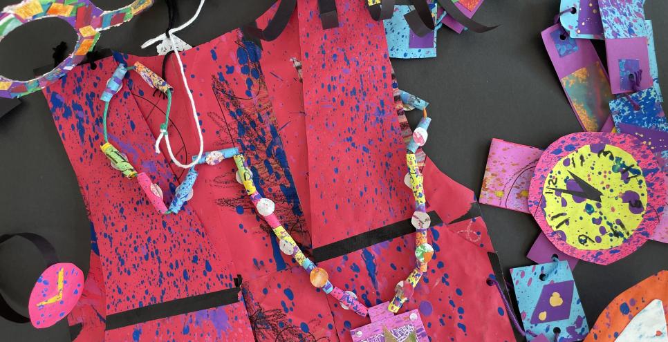 Brightly colored papers with splatter paint sculpted into necklaces, vests, glasses, hats, watches and a scarf.