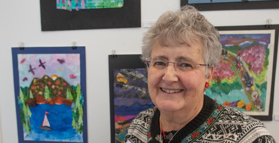 Adult art student standing in front of art.