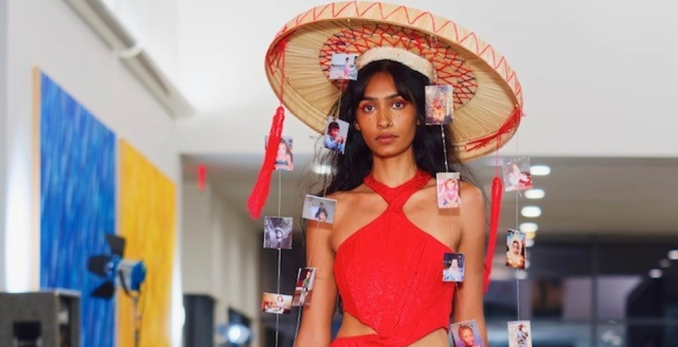 Model walking down the runway with yellow skirt and red halter top
