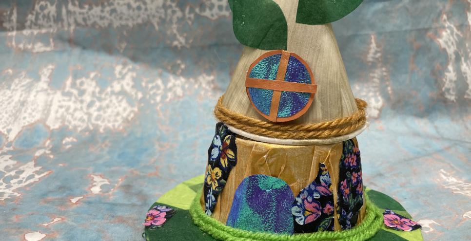 A fairy house made out of paper obects, paper leaves, sparkly papers, green fabric patches of grass