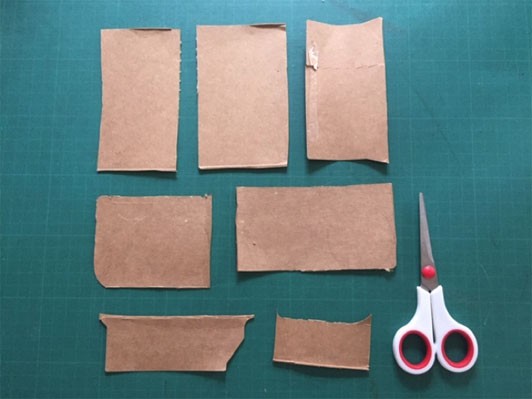 Seven rectangles of cardboard arranged on a table with a pair of scissors.