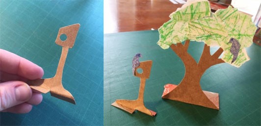 Two side by side images, the first showing a cardboard birdhouse on top of a pole, at the base is a tab that has been cut in half with one half folded forward and the other half folded back. The second image shows the birdhouse standing, supported by these tabs.  